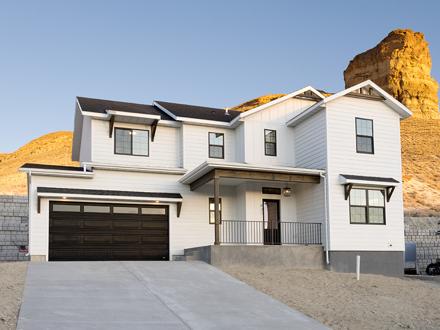 Exterior photo of charming 2-story home with 2-car garage, front porch, white siding and wood accents